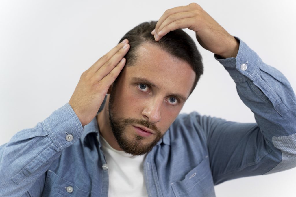 Man examining his scalp for hair loss or thinning hair.