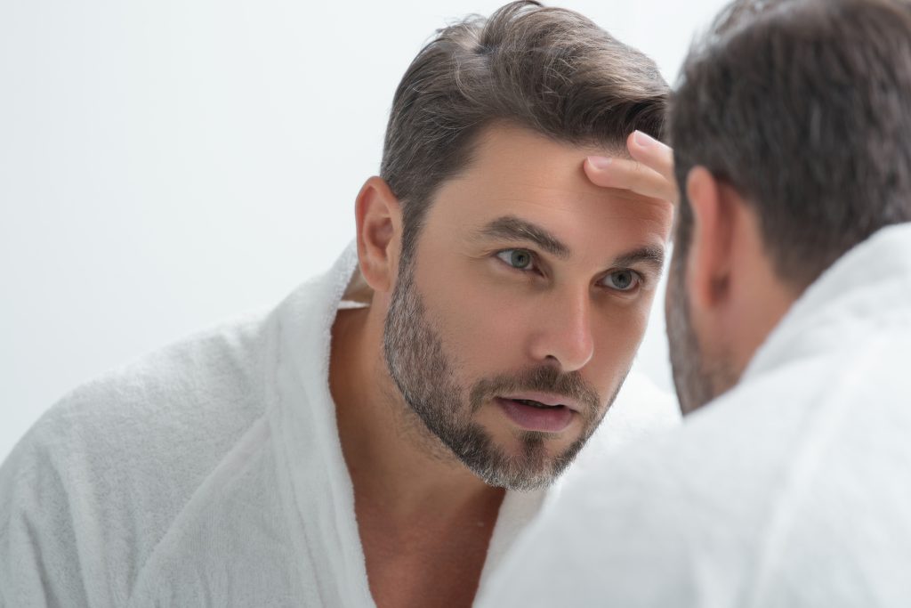 Man examining his forehead during skin consultation at clinic.