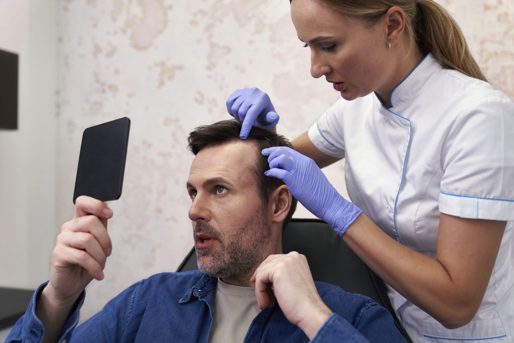 Doctor examining man's hair during a consultation at The Skin and Hair Clinic.